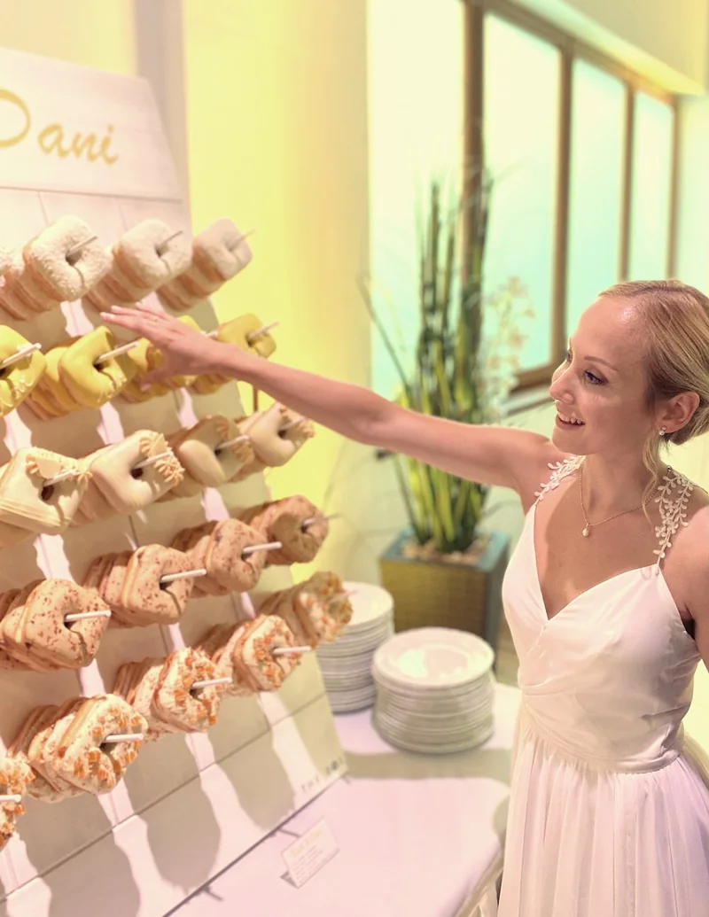 A bride at a wedding reaching for a square donut from the donut tree