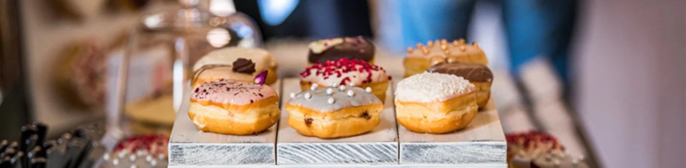 Square donuts with chocolate, berries and pistachio on a table display